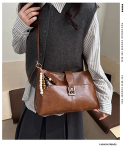 Borsa a spalla vintage marrone con ciondolo decorativo in rilievo sulla modella