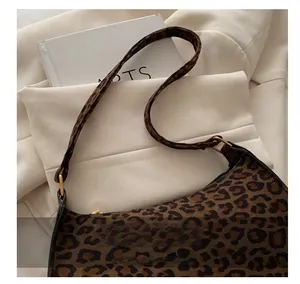 Detail of leopard print shoulder bag strap and gold metal hardware on a beige blazer