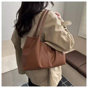 Detail of dark brown leather tote bag showing soft texture and slim shoulder strap