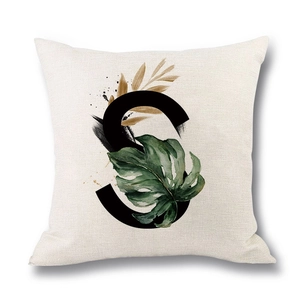 Linen cushion cover with letter S and tropical green leaves on a beige background