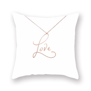 Close-up of rose gold Love cursive pendant necklace resting on a soft white cushion