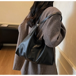 Detail of soft black leather tote bag with adjustable buckle strap on model's shoulder