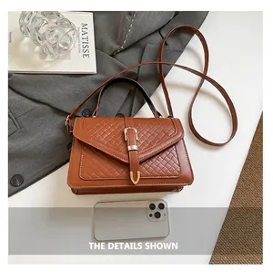 Détail du sac à main marron à texture tressée avec boucle en U dorée et bandoulière