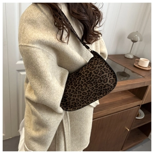 Leopard print baguette bag over the shoulder paired with a beige wool coat in a cozy setting