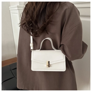 Detailed back view of a white minimalist leather handbag with adjustable strap and gold buckle