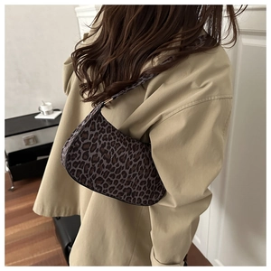 Detail of a chic leopard print crescent shoulder bag on a model in a beige coat