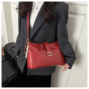 Dettaglio della borsa tote rosso scuro con fibbia argentata e perline in legno decorative