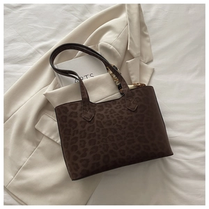 Détail du sac cabas à imprimé léopard posé sur un blazer beige et des livres d'art