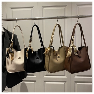 Close-up of four minimalist leather tote bags in various colors with silk scarf handles