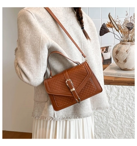 Gros plan sur la texture en cuir tressé marron et le fermoir doré du sac à main
