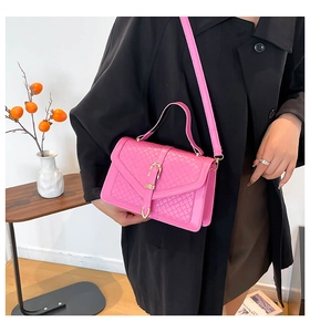 Détail macro du sac bandoulière en cuir tressé magenta avec boucle fer à cheval dorée