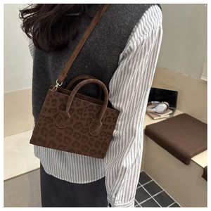 Model wearing a brown leopard print tote bag with suede texture and shoulder strap