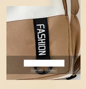 Close-up of khaki canvas shoulder bag featuring a black 'FASHION' webbing and D-ring detail