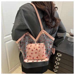 Detail view of large transparent PVC tote bag with red cherry print and pink leather trim
