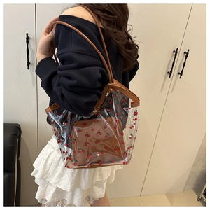 Detailed shot of transparent PVC tote bag with cherry prints and brown leather handles