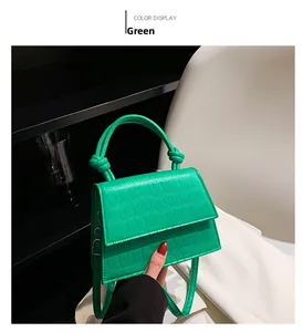 Detail of green crocodile embossed handbag with knotted handle and shoulder strap