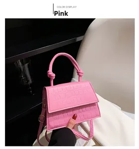Detailed view of pink crocodile-embossed handbag featuring a unique knotted handle design