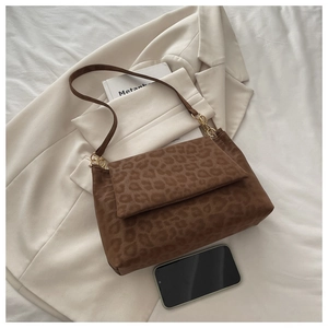 Détail du sac à bandoulière léopard avec anneaux dorés sur un blazer beige chic