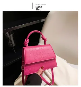 Close-up of rose red crocodile pattern leather bag with knotted handle detail