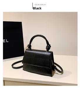 Detail of black crocodile texture handbag with twisted gold handle and flap closure