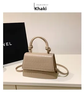 Detail of khaki croc-embossed handbag with unique knotted handle and slim strap