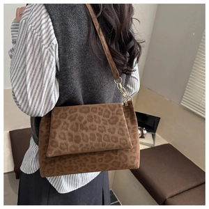 Détail du sac bandoulière léopard avec chaîne dorée porté par un mannequin féminin