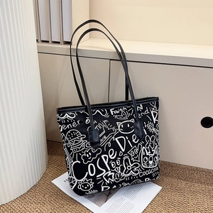 Detail shot of black tote bag with white graffiti patterns and stylish canvas texture