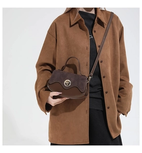 Detail showing mixed suede and smooth leather texture with round metal clasp on handbag