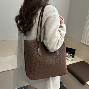 Elegante borsa tote leopardata con manici in pelle marrone indossata con cappotto beige