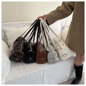 Boston barrel bags in brown black silver and beige displayed on a white sofa