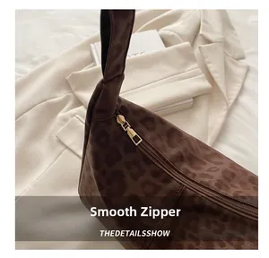 Detail of smooth gold zipper on a large leopard print crossbody bag with velvet texture