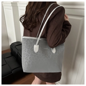 Detail of grey leopard embossed tote bag featuring silver leather straps and fashion logo