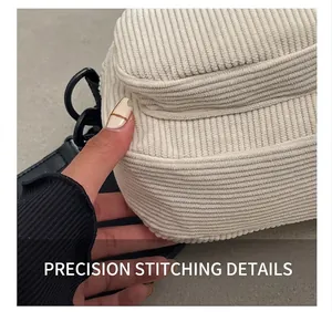 Detail view showing textured corduroy fabric and precise stitching on a beige shell bag