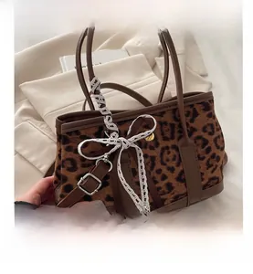Dettaglio della borsa leopardata con fiocco in pizzo bianco e manico in pelle