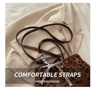 Close-up of leopard print shoulder bag with brown straps and a white lace bow detail