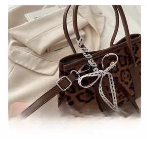 Dettaglio della borsa leopardata in peluche con tracolla in pelle e fiocco di pizzo
