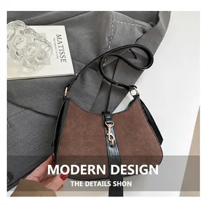 Detailed view of brown suede shoulder bag with black leather trim and golden clasp