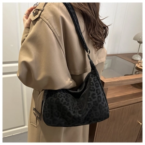 Detail of black leopard print hobo bag in soft fabric texture worn with a trench coat