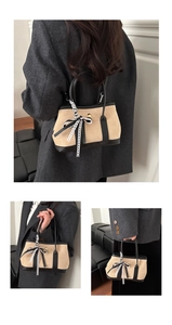 Détail d'un sac à main beige en daim avec garniture en cuir noir et lacets