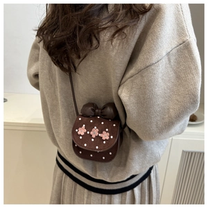 Detail of cute brown polka dot crossbody bag with 3D pink flowers and large bow