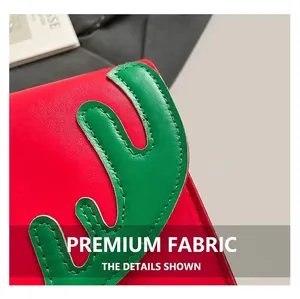 Détail du sac en cuir rouge montrant le décor de bois verts et les coutures fines