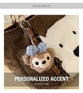 Detail of brown corduroy tote bag with plush puppy patch and decorative character charm
