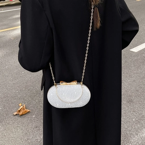 Shiny silver sequin clutch bag with metal bow clasp and chain strap for evening wear