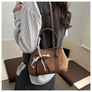 Dettaglio della borsa tote in pelle scamosciata caramello con fiocco in pizzo bianco