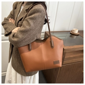 Close-up of vintage brown tote bag with litchi texture and fashion leather tag detail