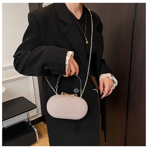 Detail of pink sequin clutch bag with bow metal handle and long gold chain strap