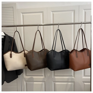 Row of four large leather tote bags in white, coffee, black, and tan on hangers