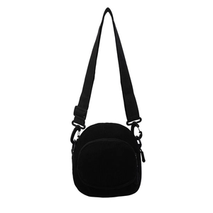 Minimalist black corduroy round crossbody bag with adjustable strap and front pocket