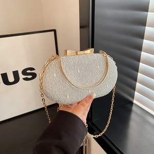 Macro shot of silver sequin evening clutch featuring a metallic gold bow clasp