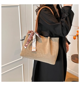 Close-up of khaki textured tote bag with elegant silk scarf on the leather handle